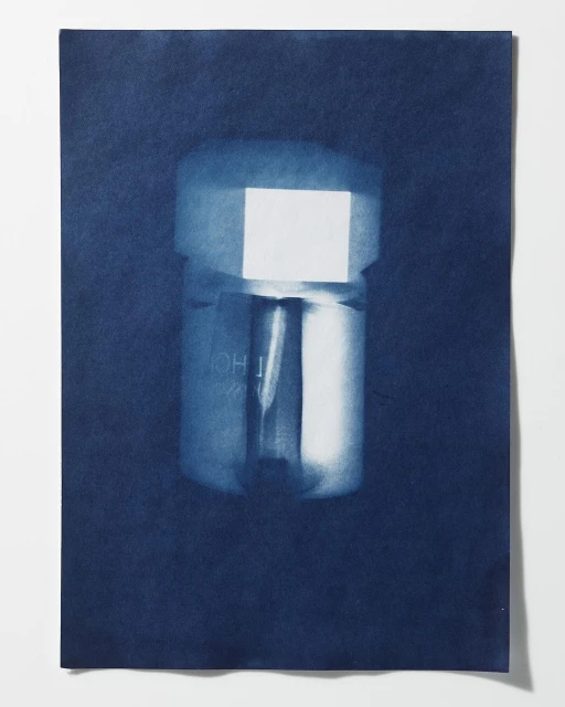 Cyanotype photograph of a metallic object, possibly a connector or fitting, set against a deep blue paper backdrop.