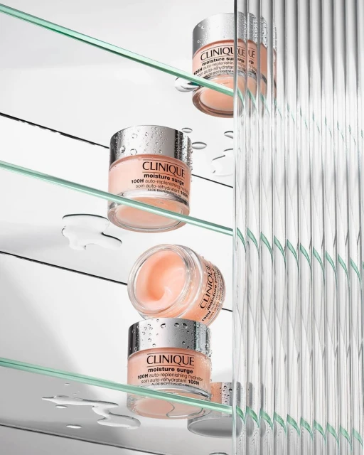 Elevated product shot featuring several jars of Clinique Moisture Surge cream stacked on glass shelves against a textured glass background.