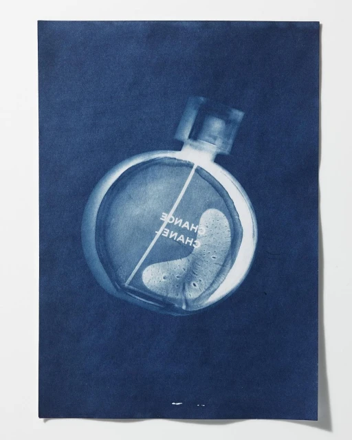 Cyanotype of a Chanel Chance perfume bottle on blue paper, centered, highlighting its round shape and the interplay of light and shadow.