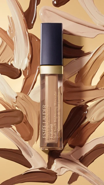 Estee Lauder Futurist Soft Touch Brightening Serum Concealer stands out against neutral tone swatches in this beauty still life.
