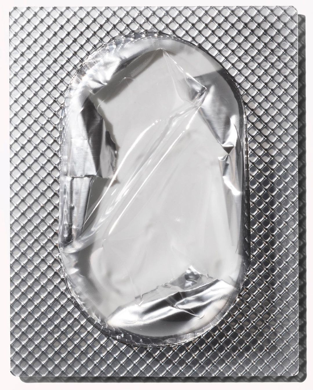 Close-up of a silver foil blister pack with an empty tablet cavity, showcasing pharmaceutical packaging and metallic texture.