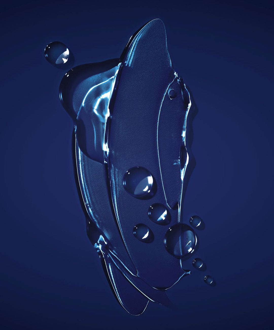 Close-up of translucent blue gel smear with water droplets on a navy blue backdrop, creating a cool, textured, and abstract visual.
