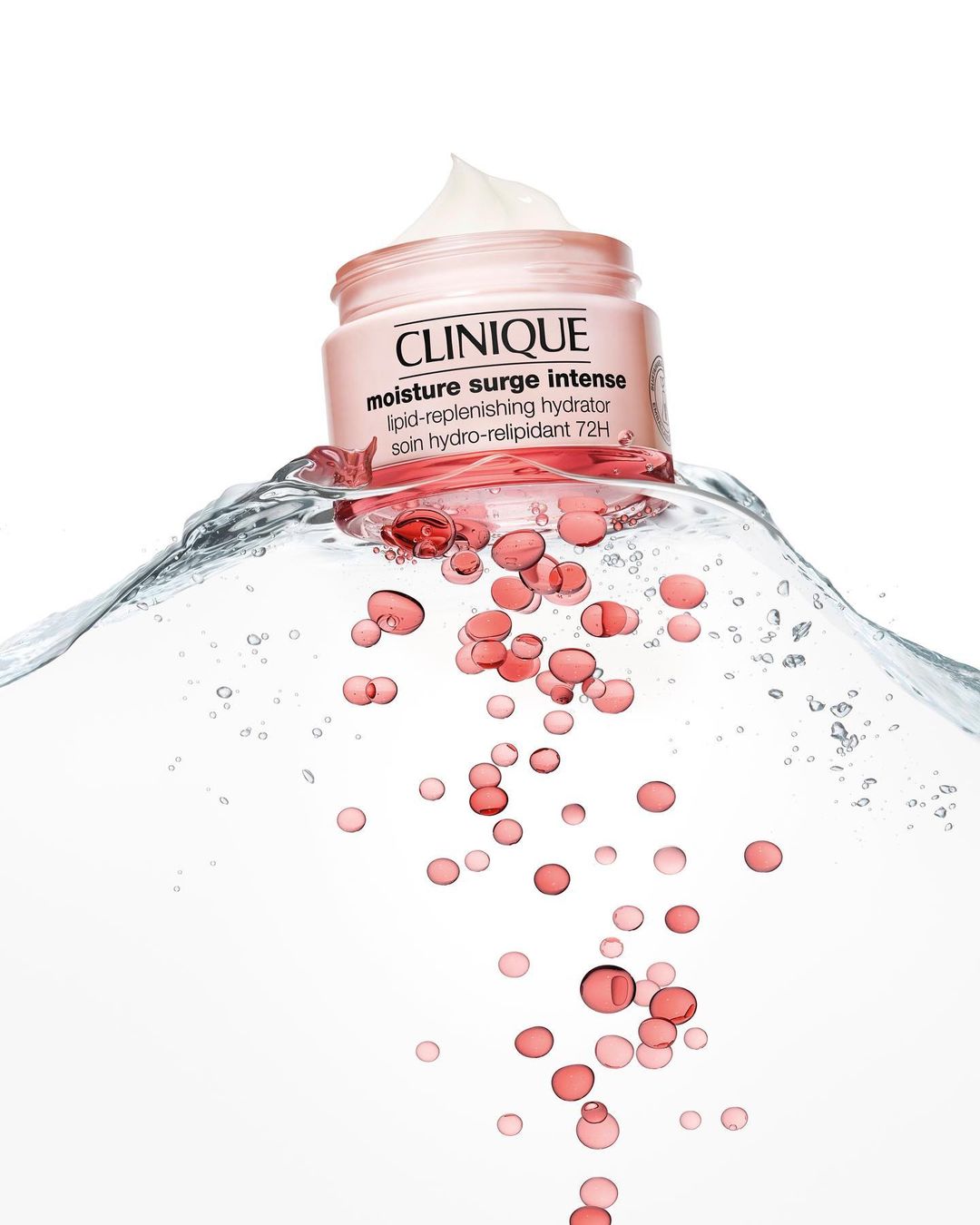 Clinique moisture surge intense cream jar shown in water with gel capsules on a white background, beauty and skincare product shot.