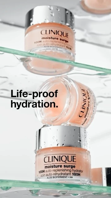 Three Clinique Moisture Surge hydrating skincare containers stacked on a reflective surface with visible water droplets, product shot.