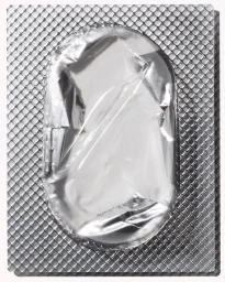 Close-up macro shot of a metallic silver blister pack with a crinkled foil backing and textured grid surface.