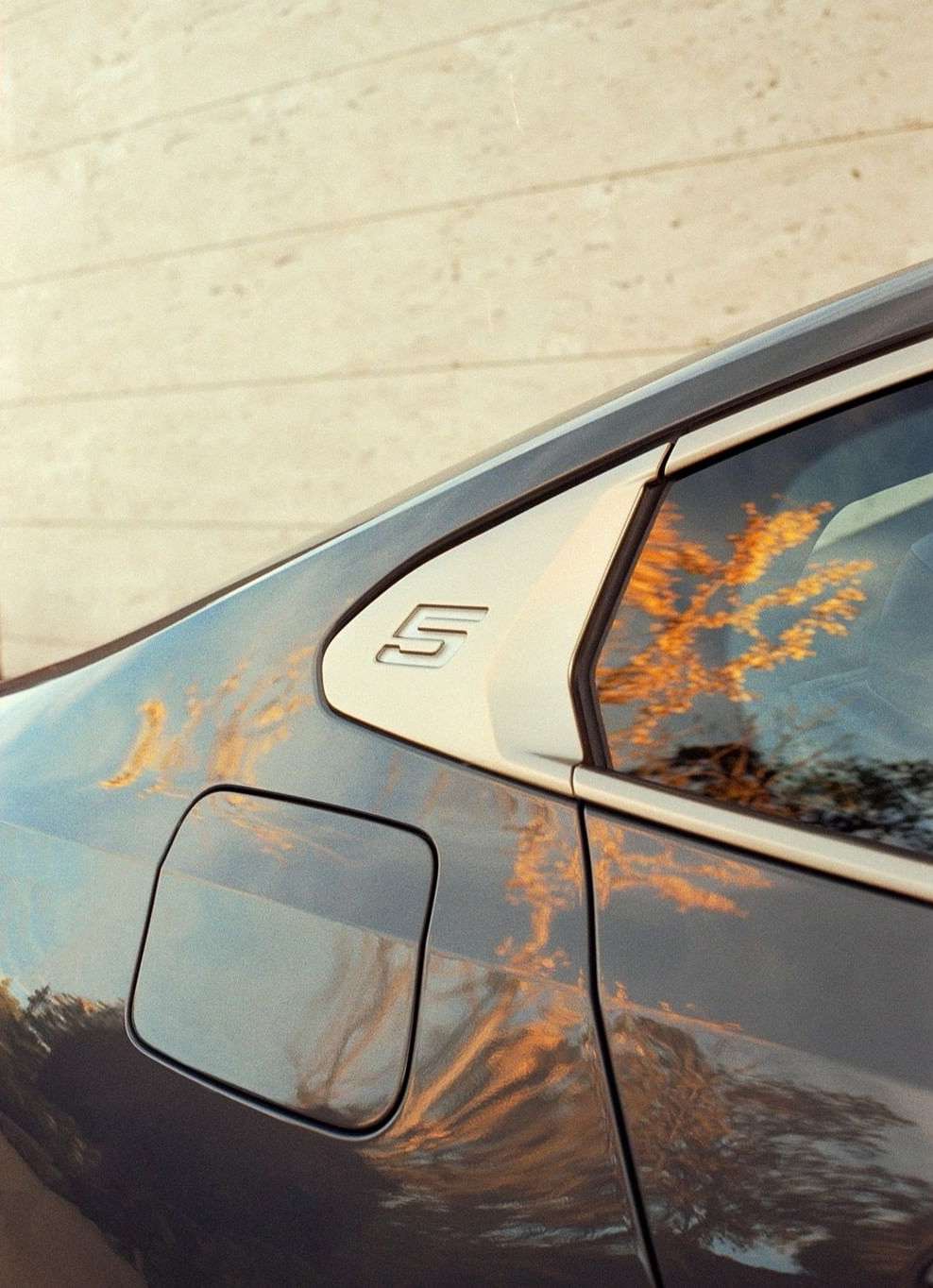 Close-up of a gray car exterior featuring a reflective surface and a streamlined design, capturing modern automotive aesthetics and style.