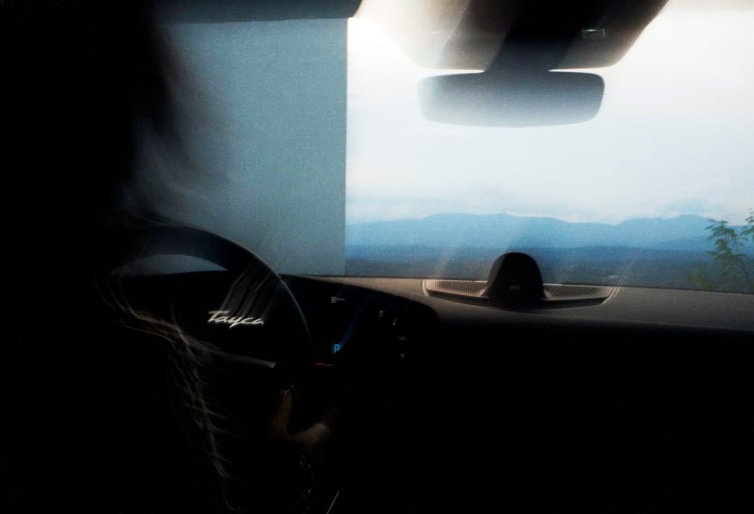 Motion blurred shot from inside a car, dashboard visible, mountains in background, capturing speed and a scenic drive.