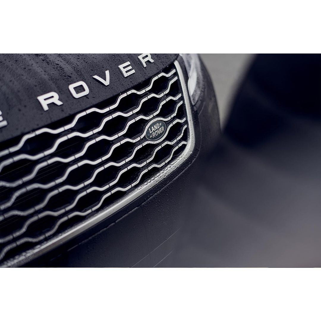 Close-up of a black Land Rover showcasing its front grill, hood, and logo, capturing the vehicle's design and brand identity.