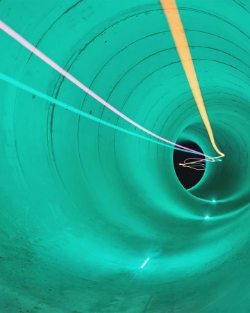 Abstract image of a tunnel with light streaks, showcasing bright neon colors, and circular geometric patterns in an indoor setting.