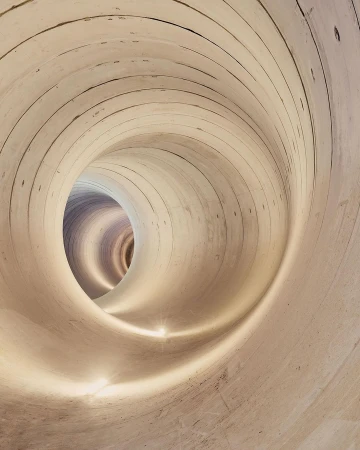 Abstract image of an illuminated tunnel with a textured surface and concentric circles receding into the distance, creating a vortex effect.