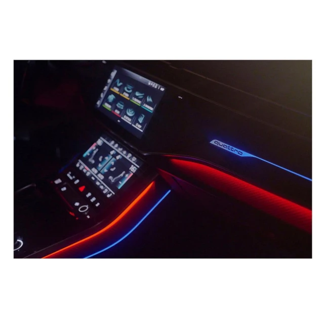 Automotive interior showcasing illuminated dashboard elements, screens, and Quattro emblem in dark ambiance with red and blue accents.