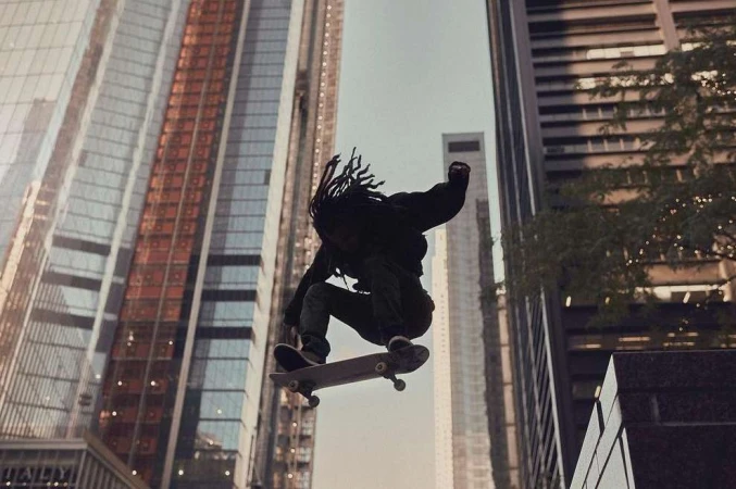 A skateboarder performs a trick mid-air in an urban setting, with tall buildings in the background, showcasing urban lifestyle and sports.