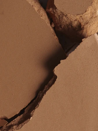 Macro view of cracked terracotta surface with rough textured edges and deep shadows