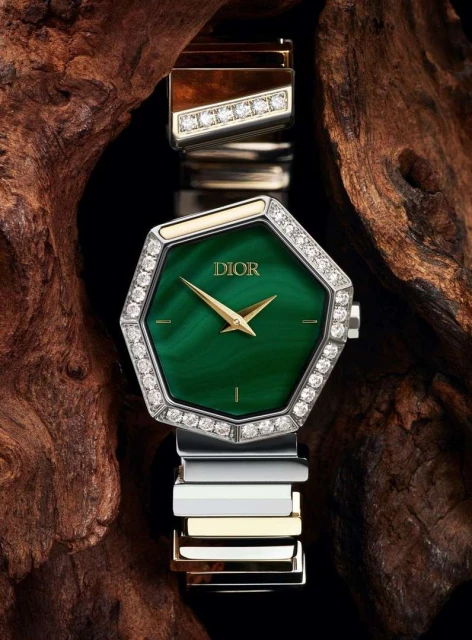 Elegant wristwatch with a green dial, diamond bezel, and two-tone metal band displayed on a dark wood background, product photography.