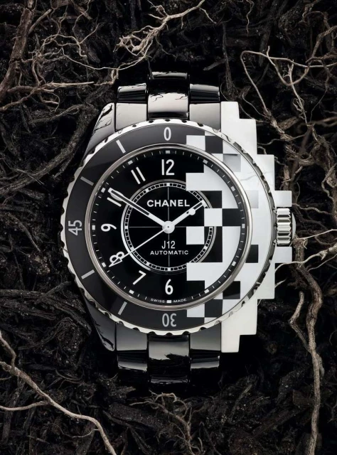 Luxury Chanel J12 watch on dark textured background with black and white checkerboard dial and stainless steel bracelet.