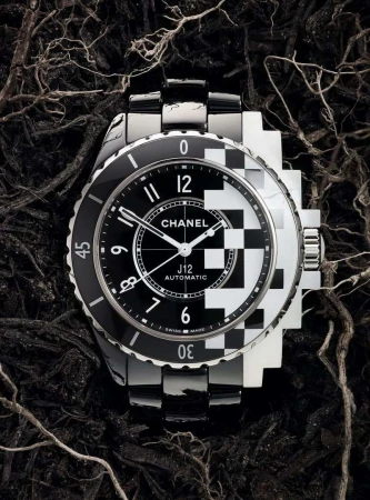 Luxury Chanel J12 watch on dark textured background with black and white checkerboard dial and stainless steel bracelet.