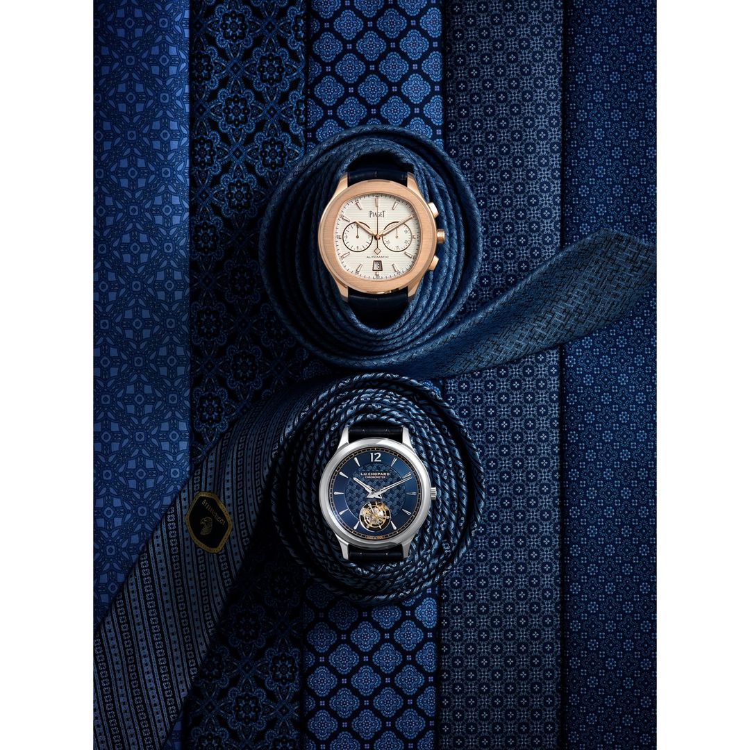 Overhead studio shot of two wristwatches nestled on folded blue patterned ties, luxury accessories, sophisticated timepieces, rich blue hues.