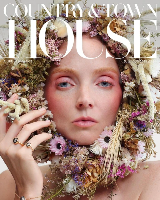 Magazine cover featuring a woman adorned with a flower wreath. The woman gazes directly forward with pink blush and eye shadow.