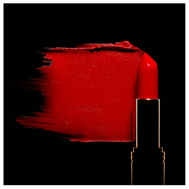 Close-up of red lipstick smear with lipstick tube on a black background, beauty product photography for cosmetics and makeup concepts.