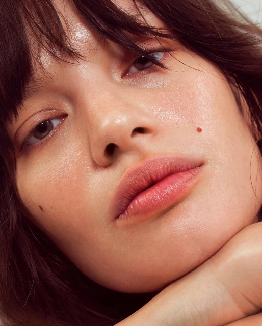 Close-up beauty portrait of a young woman with brown hair and fair skin, showcasing her facial features and minimalistic makeup.
