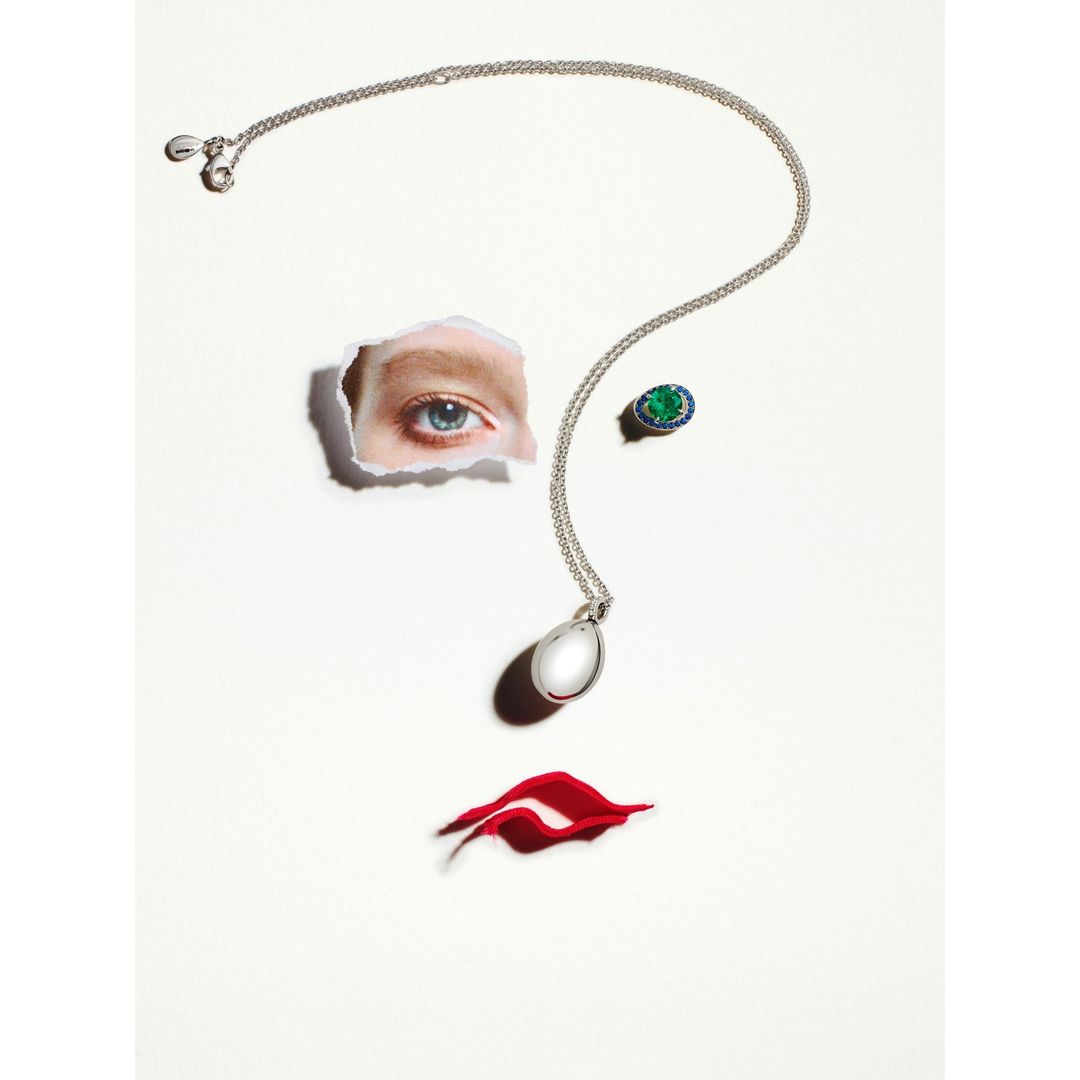 Creative fashion still life with a necklace, ring, and red paper lips forming a woman's face on a white background.