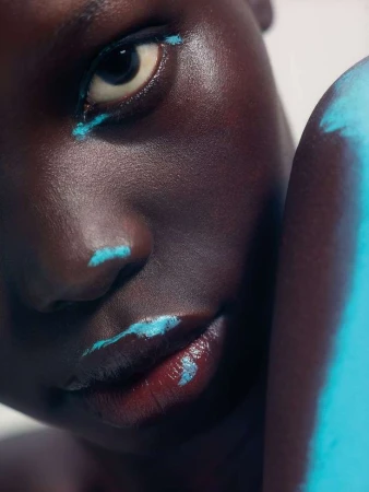 Extreme close-up portrait of a Black woman with bright blue eyeliner and matching paint on her nose and lips by Matthew Shave.