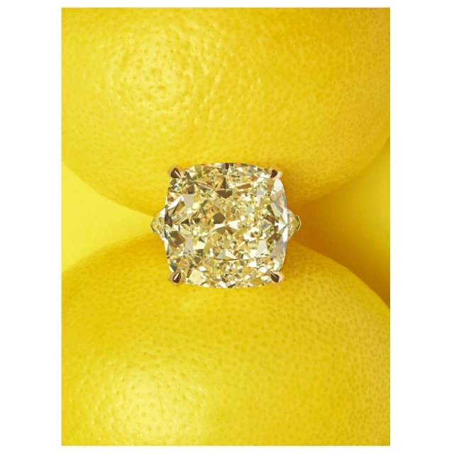 Close-up studio shot of a yellow diamond ring resting on two lemons, creating a vibrant, luxury food still life, with bright yellow tones.