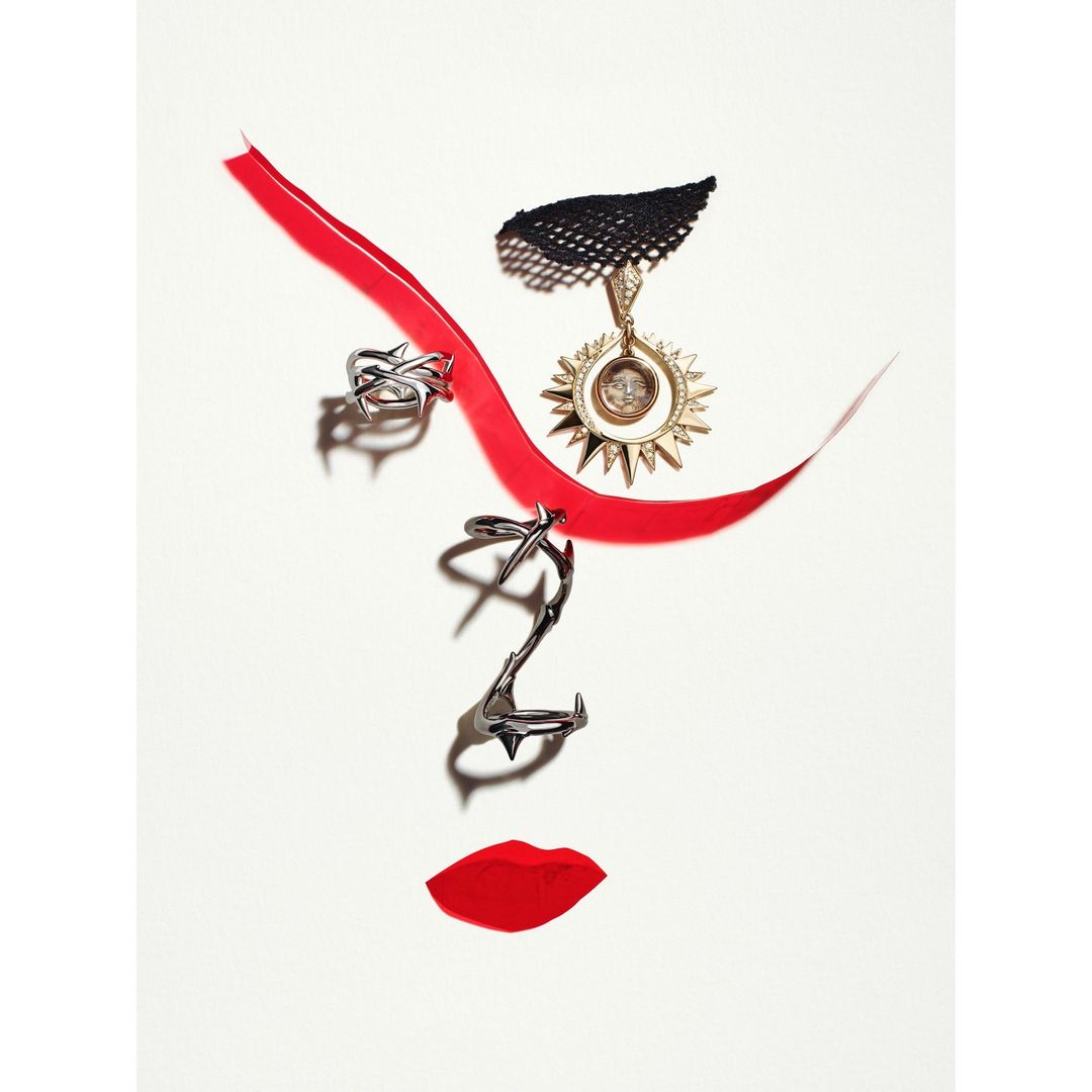 Creative abstract art: red ribbon, rings, and pendant form a face shape on a white background in a fashion and beauty still life.