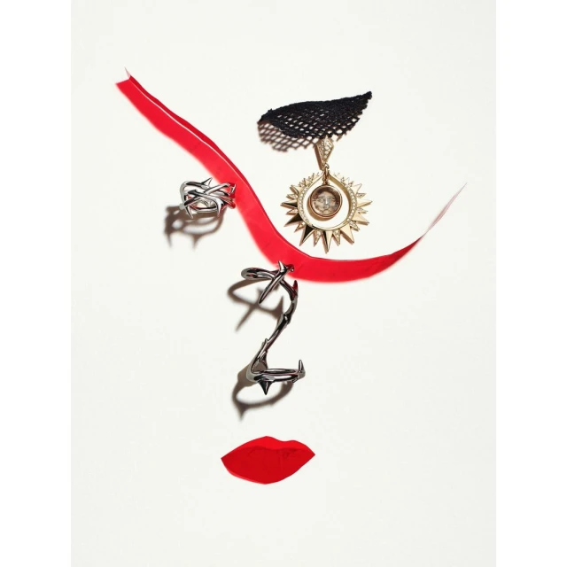 Creative abstract art: red ribbon, rings, and pendant form a face shape on a white background in a fashion and beauty still life.