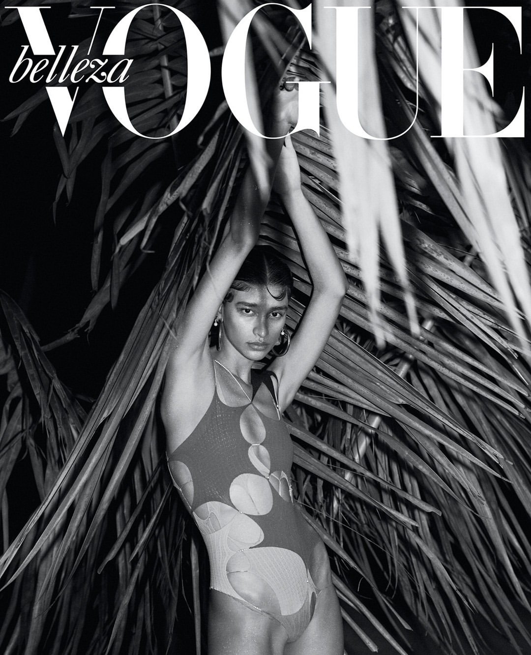Vogue magazine cover featuring a woman in a printed swimsuit with palm fronds, in a black-and-white fashion photography setting.