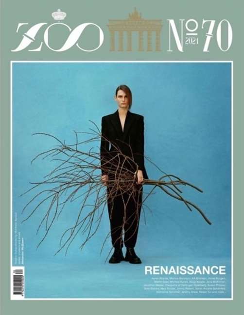 Zoo Magazine cover featuring a woman in a black suit holding bare branches against a light blue background, evoking a Renaissance theme.