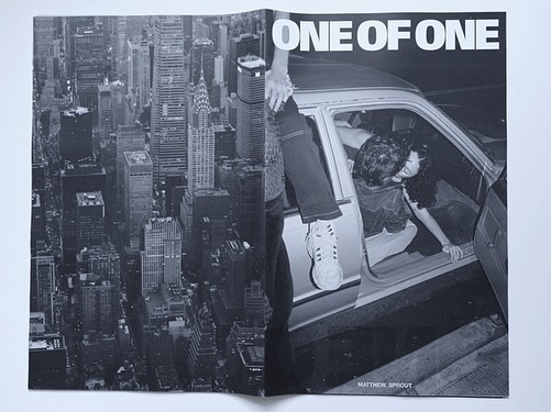 Monochrome image in a magazine spread features a couple inside a car with a cityscape view of New York City in the background.