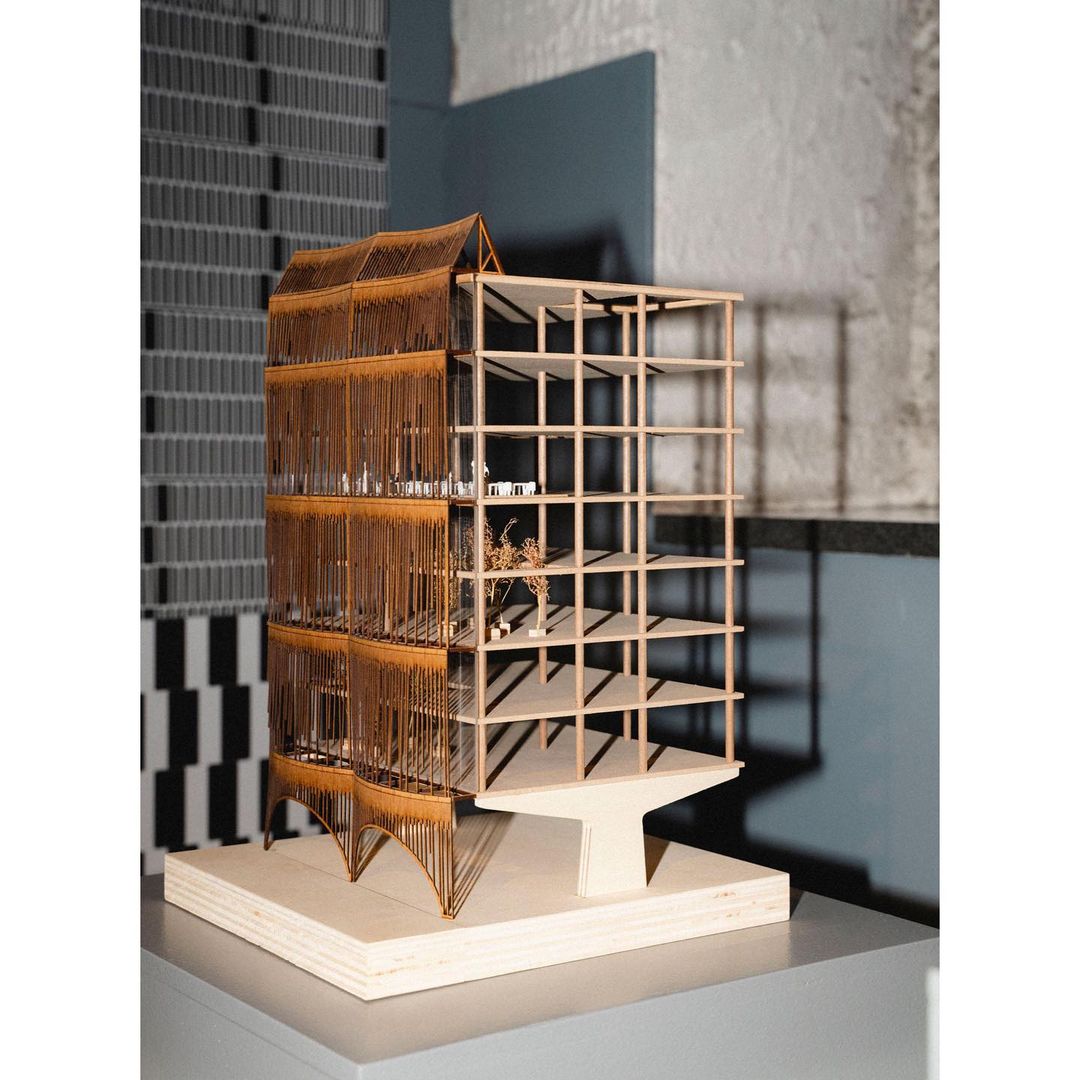 Architectural model featuring wood, metal, and concrete materials with geometric design elements, showcased in a studio-lit setting.