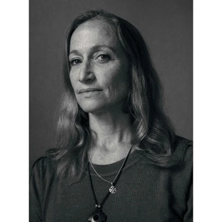 Portrait of a mature woman with long wavy hair wearing layered necklaces in a monochrome photograph