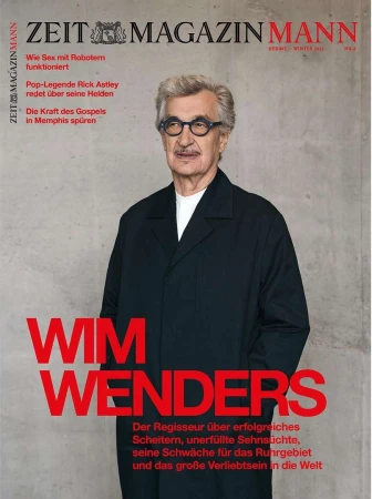 Magazine cover featuring an adult man with gray hair and glasses wearing a dark overcoat, with red text on a concrete-textured background.