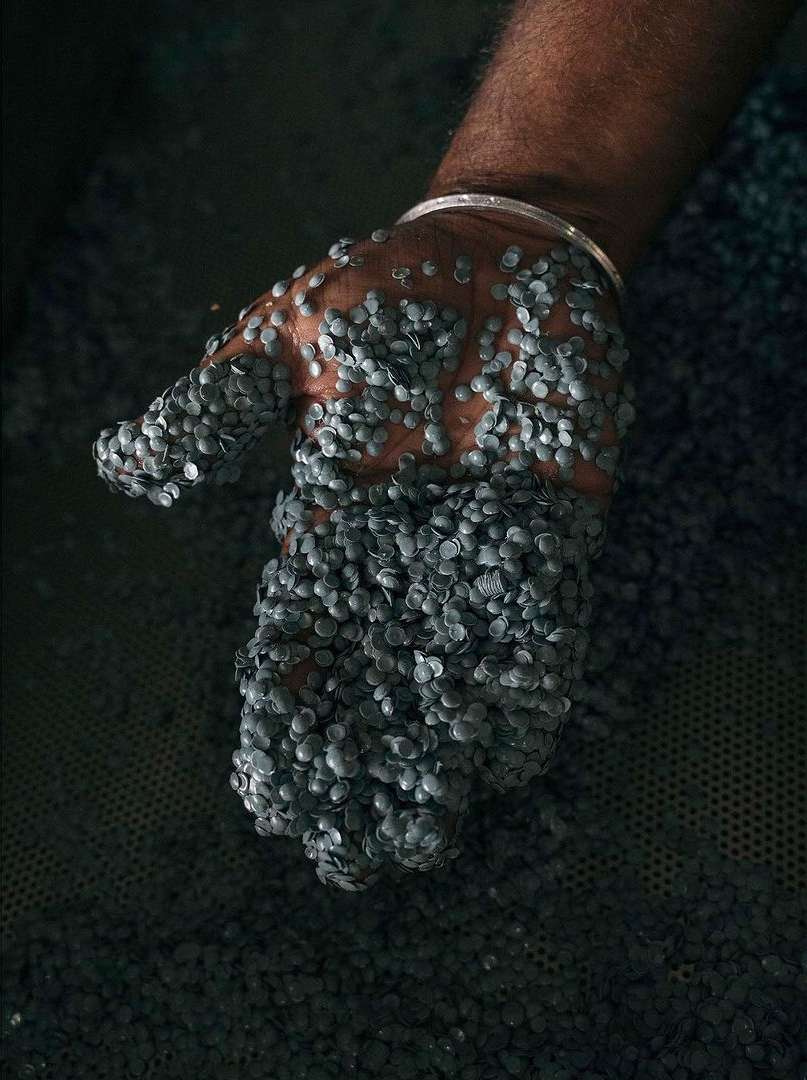 A close-up shot of an arm and hand covered in small, gray, round objects, showing texture and detail against a dark background.