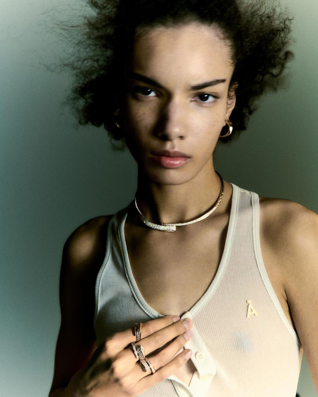 Close-up portrait of a model wearing a ribbed tank top, gold choker necklace, and rings, photographed in Paris by Matthieu Delbreuve.