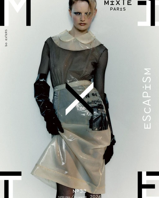 Fashion editorial cover featuring a model wearing a transparent plastic skirt and top with black mesh top, set against a white background.