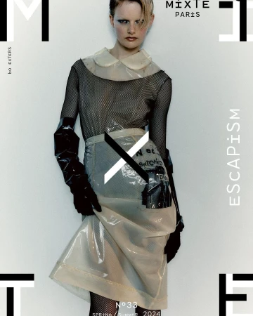 Fashion editorial cover featuring a model wearing a transparent plastic skirt and top with black mesh top, set against a white background.