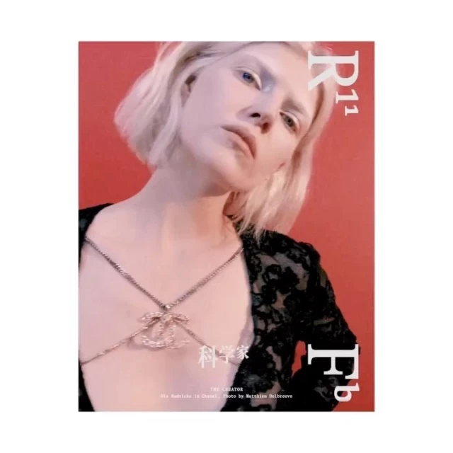 Fashion editorial shot of a fair-skinned woman with blonde hair, wearing a Chanel body chain against a red background with magazine text.