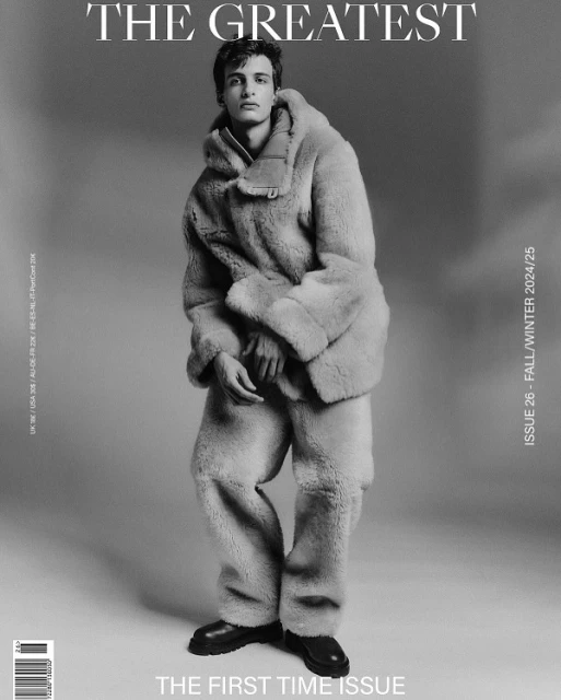 Magazine cover featuring a young adult male model wearing a light-colored fur coat and pants, posing in a studio with 'The Greatest' as the title.