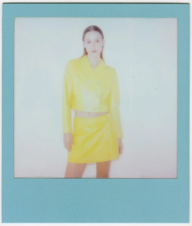 Woman in yellow outfit posing in photo-studio portrait with a blue frame. Fashion shot of stylish jacket and skirt with neutral backdrop.