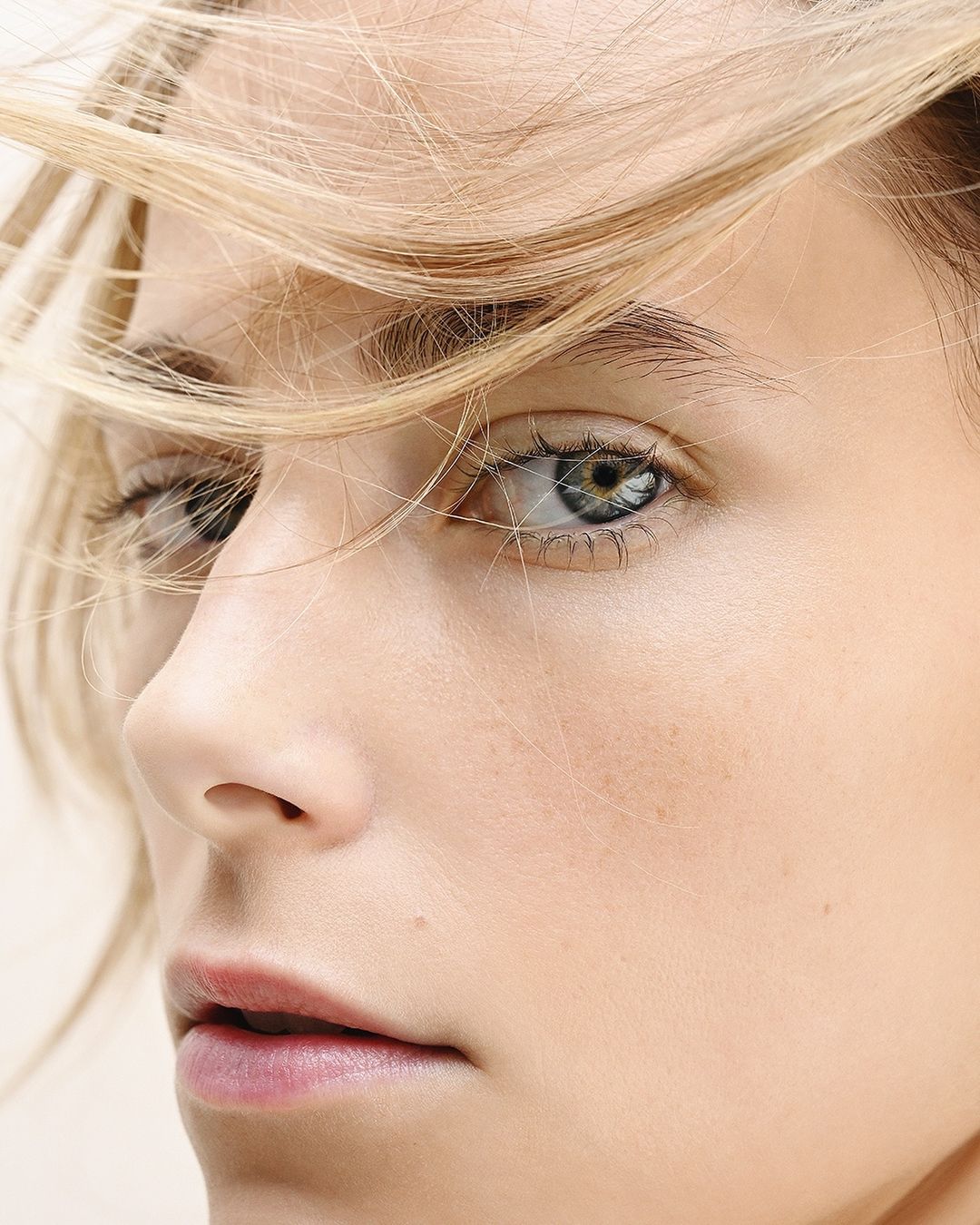 Close-up portrait of a woman with blonde hair and blue eyes, captured in natural light with a shallow depth of field. Beauty shot.