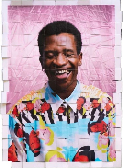 Smiling Black man wearing a patterned shirt, presented as a photo collage on a pink crumpled backdrop, eye-level portrait orientation.