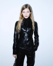 Model in a black leather jumpsuit against a plain white wall photographed by Matthieu Dortomb in Paris
