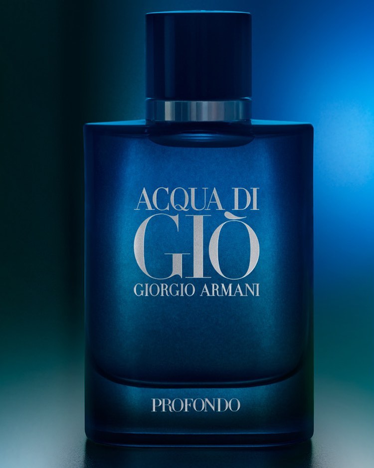 Close-up of an Acqua di Giò Profondo by Giorgio Armani fragrance bottle in a dark blue hue, set against a softly lit background.