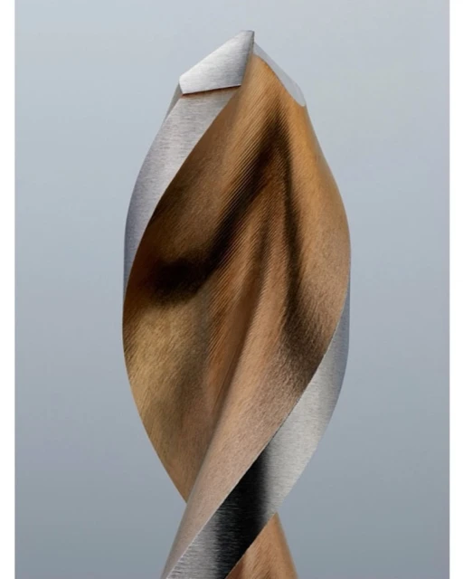 Close-up studio shot of a drill bit with a bronze-colored body and silver edges. The drill bit is set against a plain grey background.