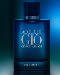 Blue glass fragrance bottle with dark cap and embossed silver lettering against a gradient blue and teal background