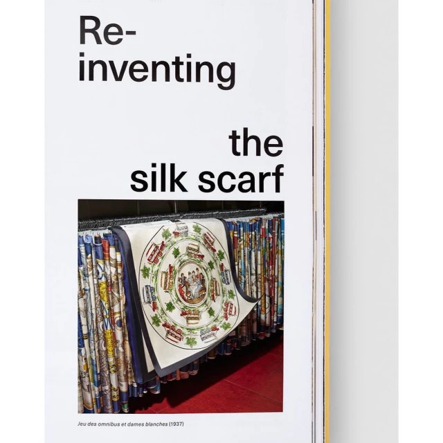 Display of silk scarves with graphic prints hanging on a rack. One scarf is slightly pulled forward. Magazine article with title text.