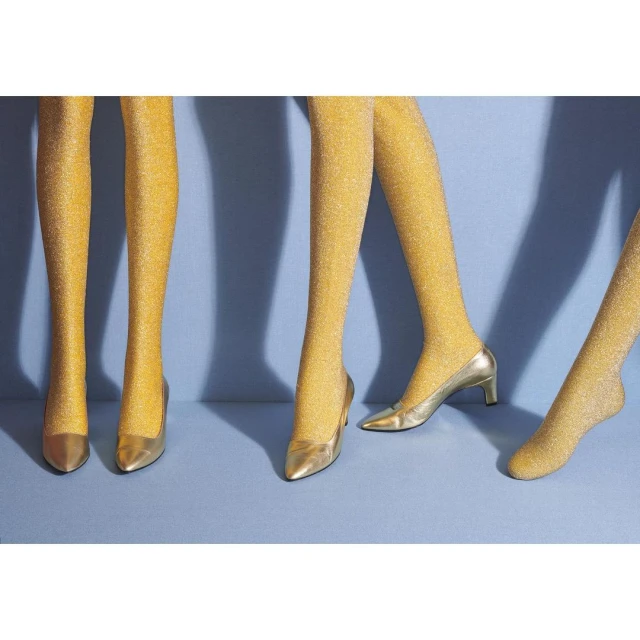 Three pairs of mannequin legs wearing glittery gold tights and matching gold high heels on a light blue background.